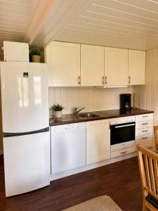 a kitchen with white cabinets and a white refrigerator at Vikinggrenda 5C - walking distance to everything - ski in and out in Trysil