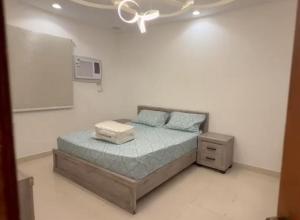 a bedroom with a bed and a white wall at الوجه مخطط 110 in Al Wajh