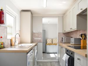 a kitchen with white cabinets and a sink at Newstead Cottage in Weymouth +13 photos