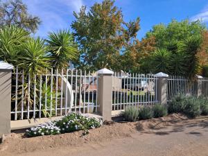 a white fence with some plants and trees at Ons Dorpshuis Beaufort West in Beaufort West