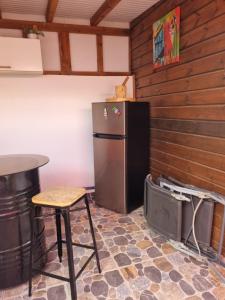 a refrigerator in a room with a table and a stool at Charmant studio d'invité - Baie-Mahault in Baie-Mahault