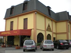 zwei Autos, die vor einem gelben Gebäude geparkt sind in der Unterkunft Aer Hotel Malpensa in Oleggio