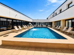 ein großes Schwimmbecken mit Liegestühlen und einer Wasserrutsche in der Unterkunft Best Western Hotel Garda in Affi