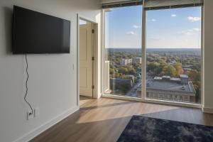 a living room with a flat screen tv and large windows at Condo in downtown oak city highrise in Raleigh