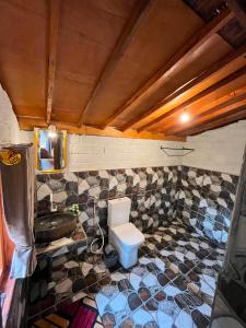 a bathroom with a toilet and a tiled wall at Fuma Bungalow Tetebatu in Tetebatu