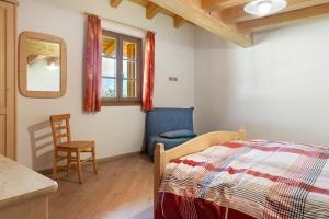 a bedroom with a bed and a chair and a window at Agritur Maso Bornie in Grauno