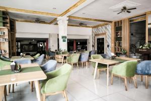 a restaurant with wooden tables and green chairs at Melasti Kuta Beach Hotel & Spa in Kuta