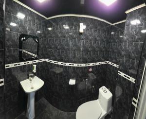 a black tiled bathroom with a toilet and a sink at Olympic Hostel in Yerevan