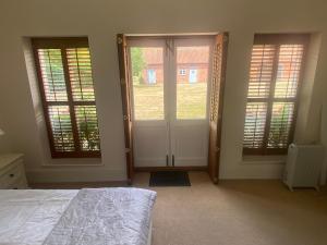 a bedroom with a bed and two french doors at Lavender Cottage in Long Bennington +1 photo