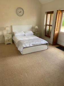 a bedroom with a bed and a clock on the wall at Lavender Cottage in Long Bennington