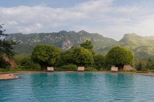a pool of water with mountains in the background at Pung-Waan Resort in Sai Yok