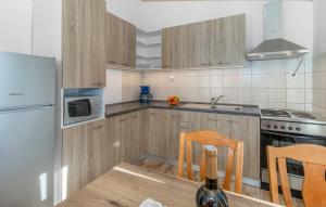 a kitchen with wooden cabinets and a table with chairs at Apartmani s dvije spavaće sobe 4 osobe in Selce