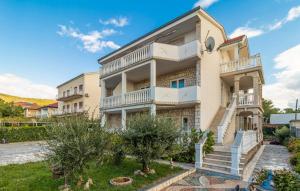 a large white building with stairs in a yard at Apartmani s dvije spavaće sobe 4 osobe in Selce
