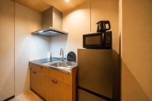 a kitchen with a sink and a microwave on top of a refrigerator at 緑翠-Ryokusui- in Beppu