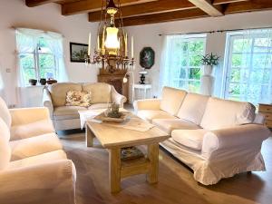 a living room with white furniture and a chandelier at Landhaus Hüttblek in Hüttblek