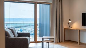 ein Wohnzimmer mit Sofa und großem Fenster in der Unterkunft Pattùs Hôtel in Saint Aubin Sauges
