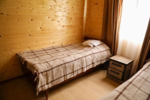 a bedroom with a bed in a wooden wall at Guest House Mercury in Khulo
