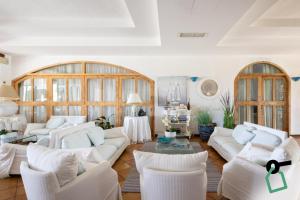 a living room with white couches and a table and chairs at Hotiday Baja Sardinia Saline in Baja Sardinia