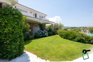 a house with a yard with a large hedge at Hotiday Baja Sardinia Saline in Baja Sardinia