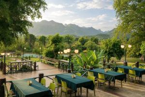 a restaurant with tables and chairs and mountains in the background at Pung-Waan Resort in Sai Yok