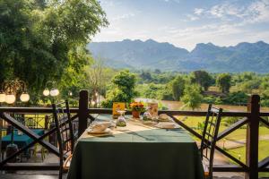 a table with a green tablecloth and chairs with mountains in the background at Pung-Waan Resort in Sai Yok +86 photos