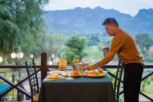 a man standing at a table with plates of food at Pung-Waan Resort in Sai Yok