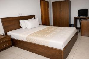 a bedroom with a large bed and a television at Hotel Murex in Brazzaville +4 photos