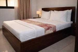 a bedroom with a large bed with white sheets at Hotel Murex in Brazzaville