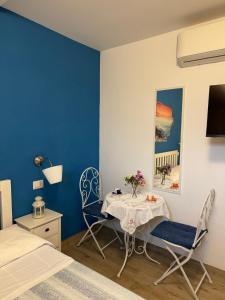 a bedroom with a table and two chairs and a blue wall at B&B Villa Jasiga in Fregene