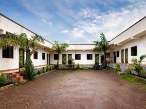 a large white building with palm trees in front of it at Hotel Tiger Paradise in Mahirāvani