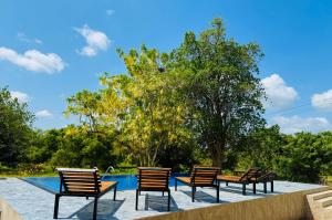 a group of chairs sitting next to a swimming pool at Sungreen Cottage Sigiriya in Sigiriya