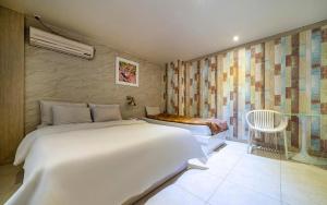 a bedroom with two beds and a chair in it at Hotel Fiona in Seoul