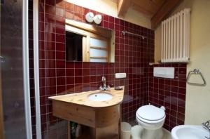 a red tiled bathroom with a sink and a toilet at Chalet Motta in Valtournenche +3 photos