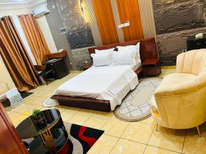 ein Hotelzimmer mit einem Bett und zwei Stühlen in der Unterkunft Complexe NESSA SARL in Jaunde