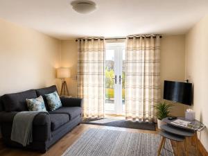 a living room with a couch and a sliding glass door at Howgills Apartments in Sedbergh