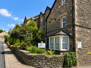 a stone building with a stone wall next to a street at Howgills Apartments in Sedbergh