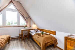 a bedroom with a bed and a desk and a window at Willa Pod Wierchem in Bukowina Tatrzańska