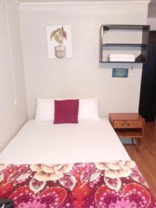 a bedroom with a white bed with a purple pillow at Apartamentos Caimán 3 in Tortuguero