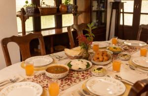 a table with plates of food and glasses of orange juice at amã Stays & Trails - Fairholme Bungalow ,Yercaud in Yercaud