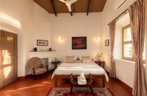 a bedroom with a bed and a chair and a window at amã Stays & Trails - Fairholme Bungalow ,Yercaud in Yercaud