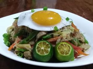 a plate of food with an egg on top of vegetables at Bermuda Beach Resort in Lagob