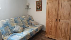 a living room with a blue couch and a wooden cabinet at La glycine in Sahune