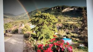 a rainbow over a mountain with flowers and a road at La glycine in Sahune +5 photos