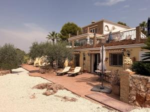 a house with a patio with an umbrella and chairs at Finca Sonrisa in Alhaurín el Grande