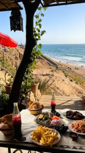 a table with plates of food and the beach at Fantastique Appartement avec piscine sur la plage de Achakar de Tanger - proche du Cap Spartel & la Grotte d'Hercule de TANGER in Tangier
