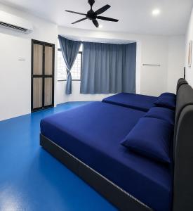a bedroom with a blue bed with a ceiling fan at CZi BOUTIQUE HOTEL SG SIPUT in Sungai Siput