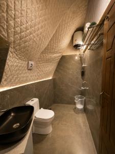 a bathroom with a black toilet and a sink at Glamp by Edge Resort Premium Luxury Domes with Mountain Views in Mussoorie