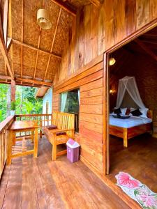a wooden cabin with a bed and a desk in it at Aulia Bungalows Tetebatu in Tetebatu