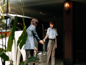 Eine Frau hält die Hand einer Frau mit einem Koffer in der Unterkunft 十二ホテル -福岡空港- in Fukuoka