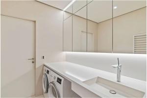 a white bathroom with a sink and a washing machine at Royal Hamilius Luxury 1 bed in Luxembourg +3 photos